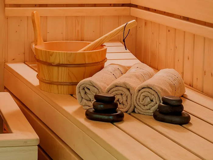 Sauna z drewnianym cebrzykiem, ręcznikami i kamieniami do masażu
